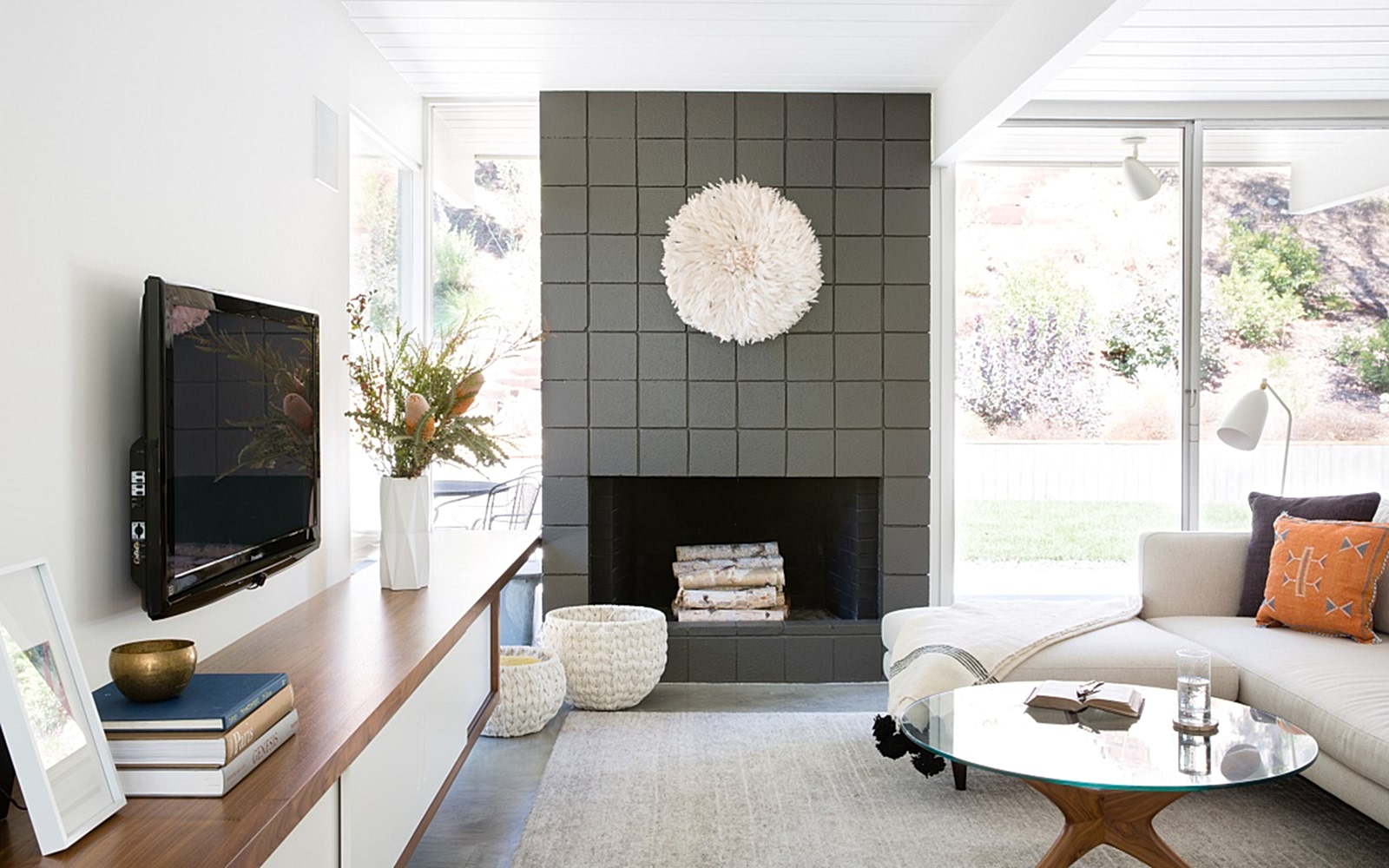 Side view of a living room with a cream sofa facing a TV mounted on the wall. 