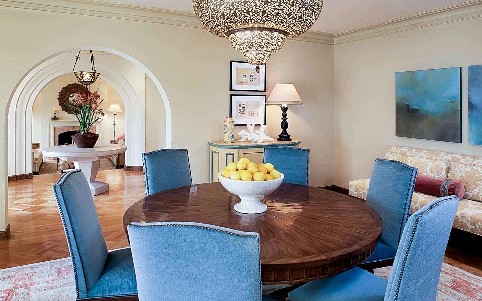 Mediterranean-style dining room with a round wood table and blue chairs. 