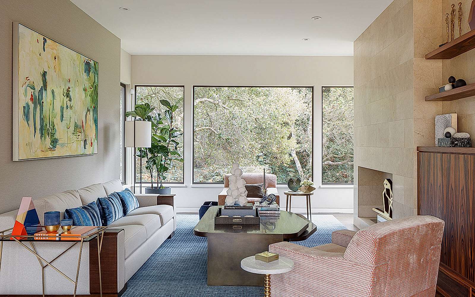 Side view of a living room with a beige sofa, pink armchair, and a large fireplace. 
