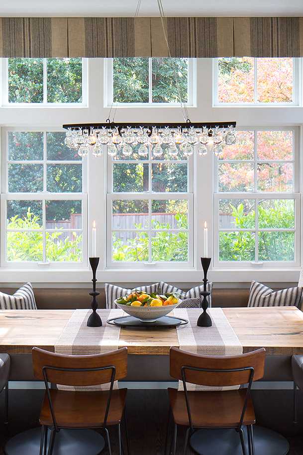 View of a dining nook. A chandelier hangs over the center of the dining table. 
