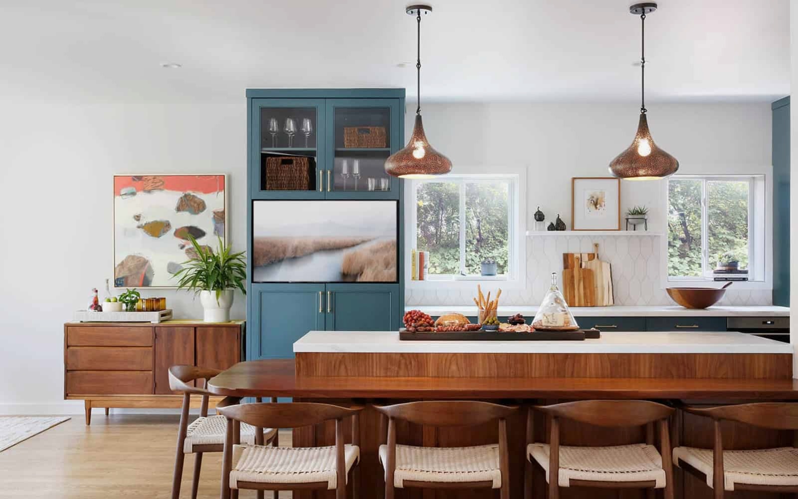 A bright Rockridge Tudor home in Oakland features warm wooden bar seating, global-influenced pendant lighting, and abstract art.