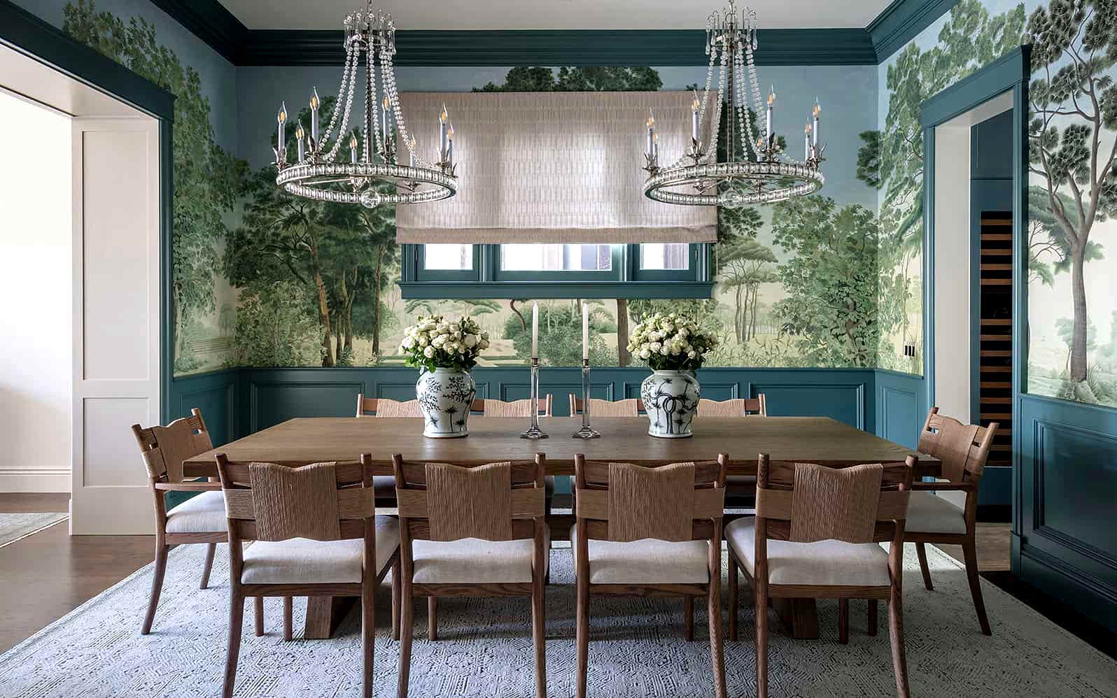 Formal dining room with custom scenic wallpaper, teal wainscoting, crystal chandeliers, and a modern oak dining table — a refined fusion of classic Victorian charm and modern luxury.